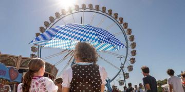 Wiesn-Start bei strahlendem Sonnenschein und Temperaturen bis 30 Grad. Besucherinnen schützen sich am Samstag mit einem Schirm vor der Sonne.
